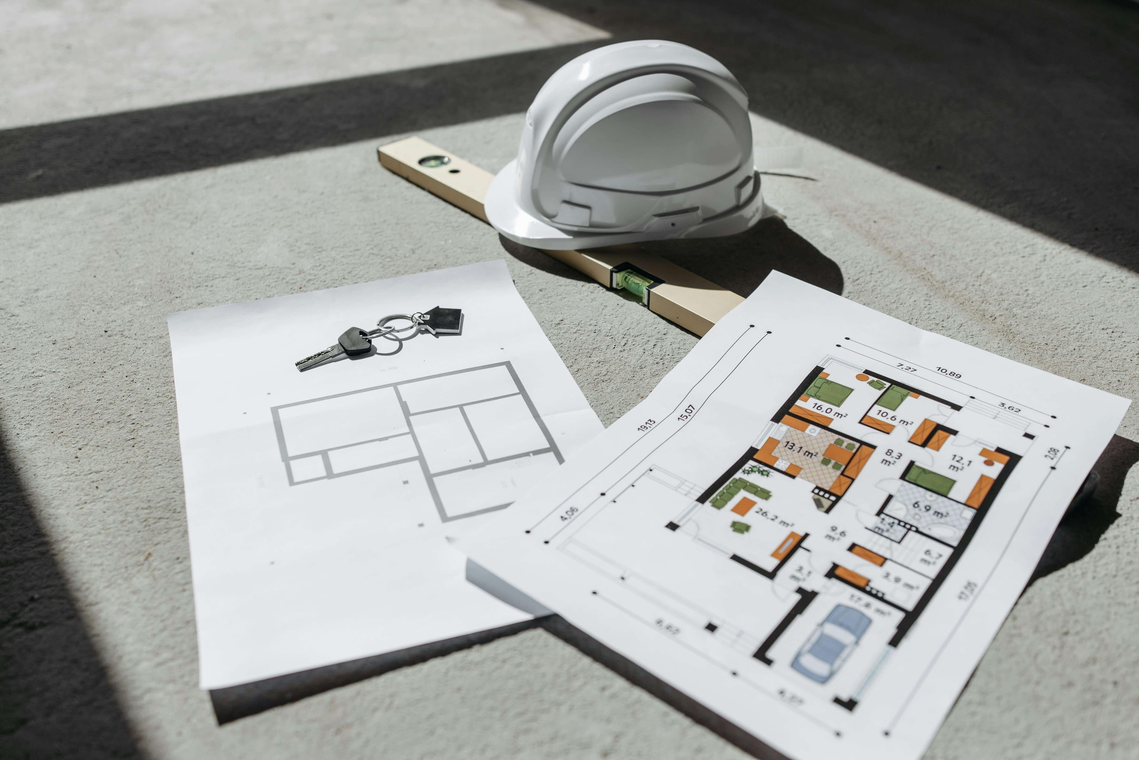 Hard hat and house plans on a worksite — planning and scope