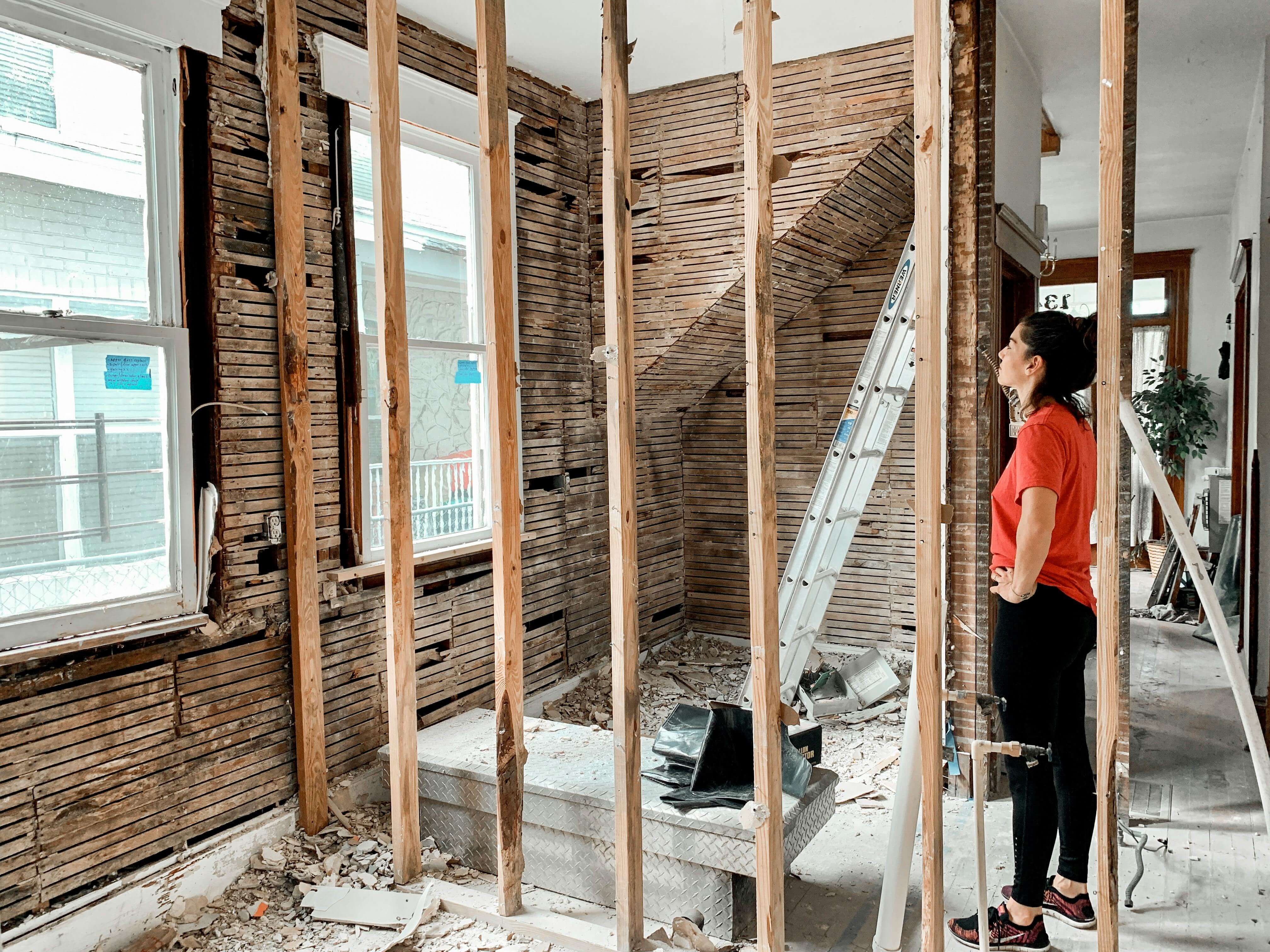 Active renovation with exposed framing and a project owner observing the work